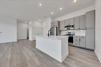 A modern kitchen with a white island and wooden floors at Luxe 360 on Centerpointe Apartments, Virginia, 23114